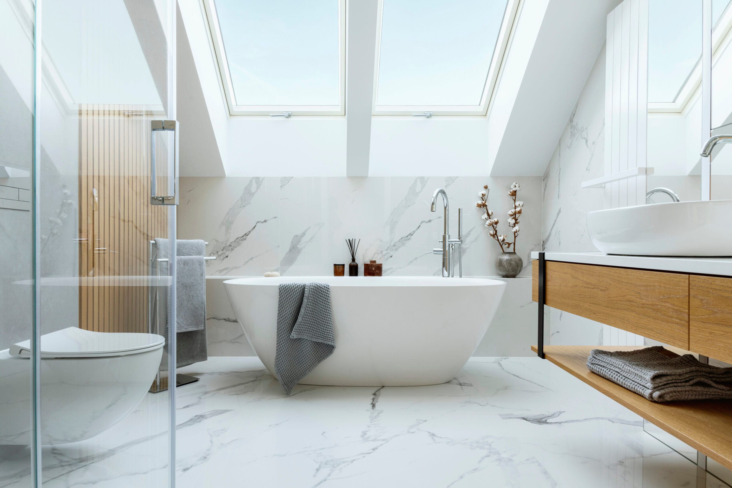 Modern bathroom with marble panels, freestanding bathtub, and roof window, showcasing home renovations Tampa FL style.